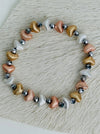 Tri-tone metallic beaded elastic bracelet in gold, silver and rose gold tones with grey spacer beads, displayed on a white background.