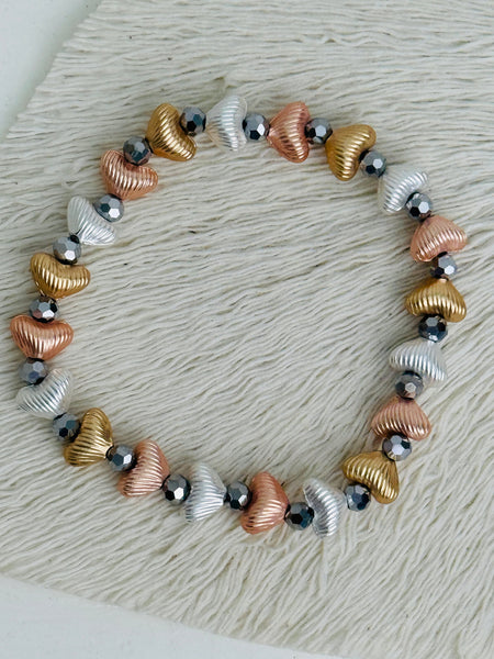 Tri-tone metallic beaded elastic bracelet in gold, silver and rose gold tones with grey spacer beads, displayed on a white background.