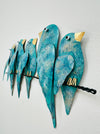 Side angle view of hand-painted turquoise metal birds on a branch wall sculpture