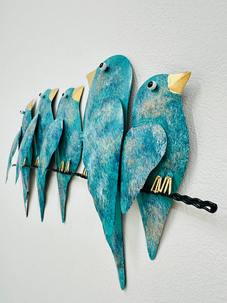 Side angle view of hand-painted turquoise metal birds on a branch wall sculpture