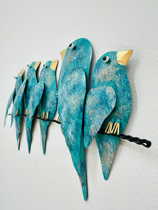 Side angle view of hand-painted turquoise metal birds on a branch wall sculpture