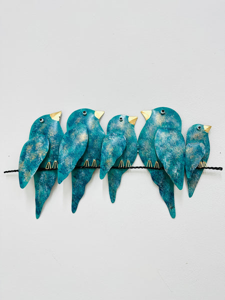 A group of hand-painted metal birds in varying shades of turquoise perched on a horizontal bar.
