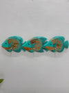 Three turquoise and gold decorative fish wall hooks mounted on a white textured wall.