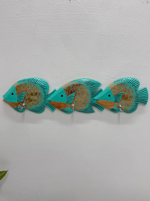 Three turquoise and gold decorative fish wall hooks mounted on a white textured wall.