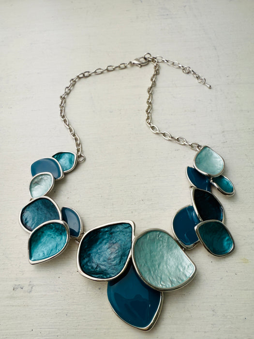 Turquoise enamel leaf statement necklace with silver-tone chain and layered leaf shaped accents, displayed on a white background.
