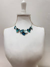 Turquoise enamel leaf statement necklace with silver-tone chain and layered leaf shaped accents, displayed on a mannequin.