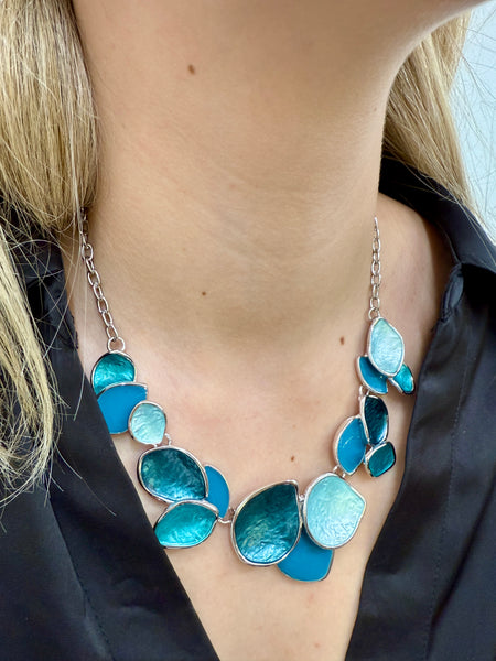 Turquoise enamel leaf statement necklace with silver-tone chain and layered leaf shaped accents, displayed on a model.