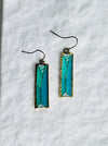 Pair of turquoise rectangular earrings on a white textured background
