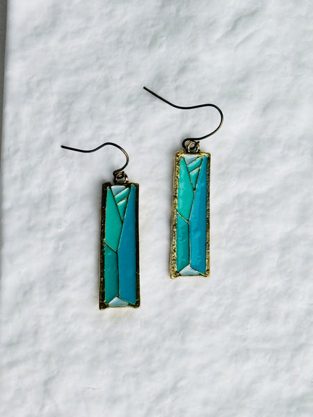 Pair of turquoise rectangular earrings on a white textured background