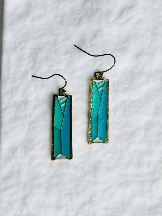 Pair of turquoise rectangular earrings on a white textured background