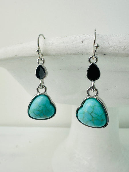 A pair of earrings featuring a heart-shaped turquoise stone and teardrop-shaped black stone