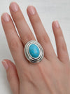 Turquoise stone ring on a hand against a white background