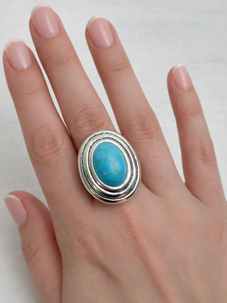 Turquoise stone ring on a hand against a white background