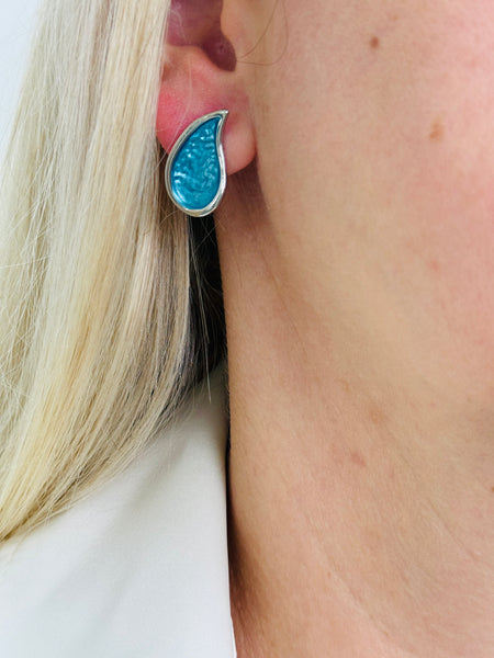 Turquoise teardrop enamel stud earrings with silver tone finish, displayed on a model.