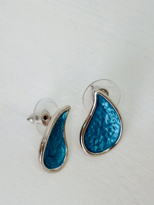 Turquoise teardrop enamel stud earrings with silver tone finish, displayed on a table.
