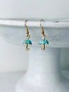 Turquoise umbrella-shaped earrings on a white stand