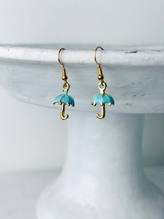 Turquoise umbrella-shaped earrings on a white stand