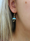 Gold earring with a blue umbrella charm worn by a person with blonde hair.
