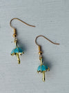 Gold and blue umbrella-shaped earrings on a gray background