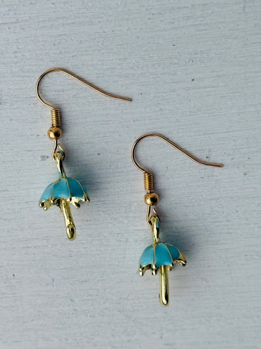 Gold and blue umbrella-shaped earrings on a gray background