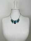 Geometric enamel necklace with layered rectangular pieces in turquoise, grey and gunmetal, on silver-tone chain beads, on a mannequin bust
