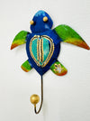 A handmade metal turtle-shaped hook with green and blue coloring and gold detailing.