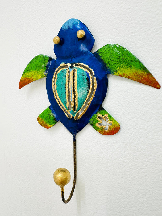A handmade metal turtle-shaped hook with green and blue coloring and gold detailing.