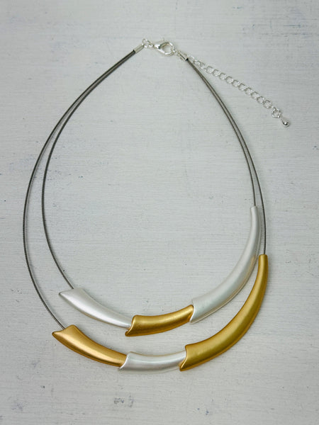 aerial view of necklace with gold and silver curved design 