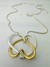 close-up of elegant two - tone intertwined heart pendant necklace on a silver chain