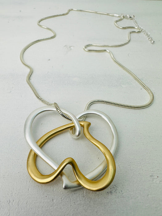 close-up of elegant two - tone intertwined heart pendant necklace on a silver chain