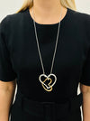 Elegant two - tone intertwined heart pendant necklace on a silver chain displayed on a mannequin