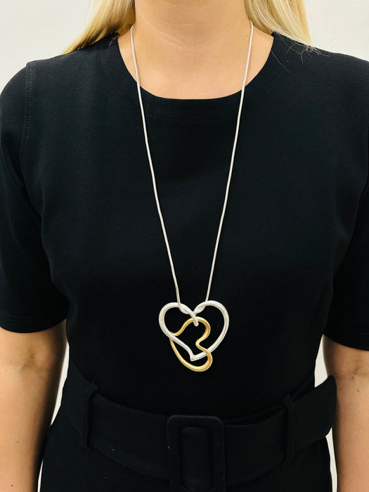 Elegant two - tone intertwined heart pendant necklace on a silver chain displayed on a mannequin
