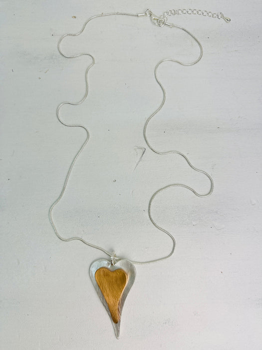close-up of two-tone long heart pendant necklace on a silver chain.