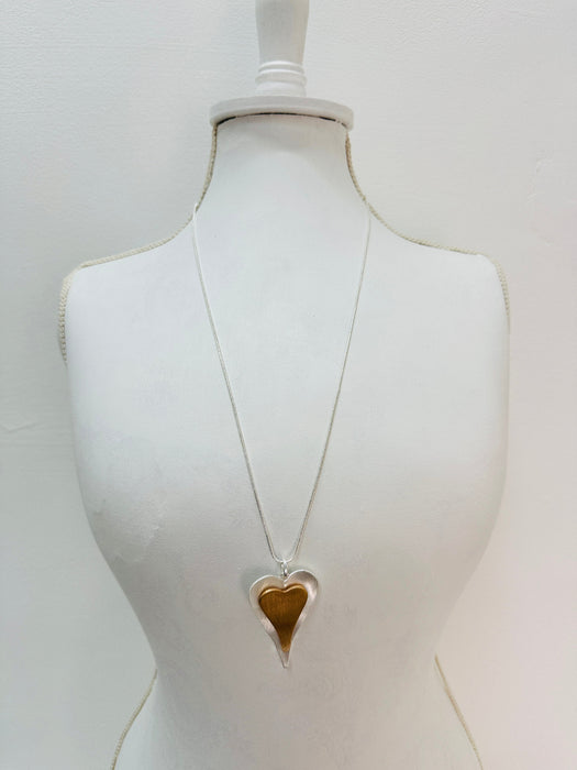 A necklace with a heart-shaped pendant displayed on a mannequin bust.