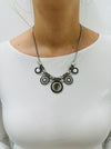 Necklace with circular design worn by a person on a white background