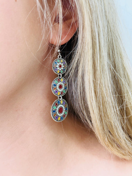 Close-up of a colorful earring worn by a person with blonde hair.