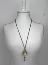 Long necklace with a vintage-style pendant on a mannequin bust against a plain background