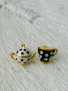 Teapot and teacup-shaped earrings on a textured white surface