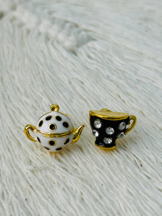 Teapot and teacup-shaped earrings on a textured white surface