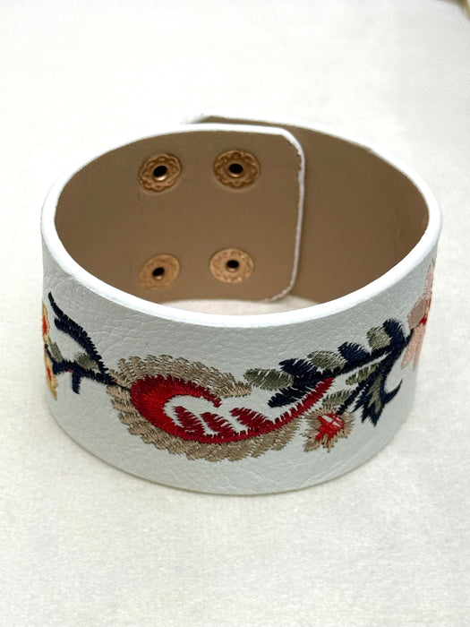 White faux leather bracelet with embroidered designs on a white background