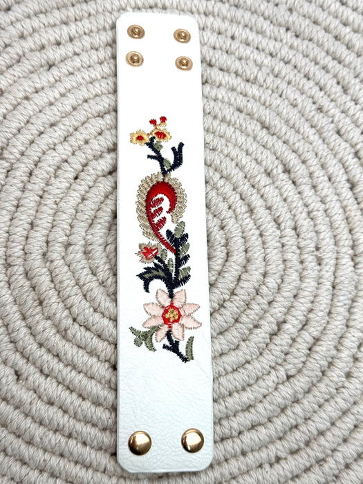 Decorative leather strap with floral embroidery on a textured surface