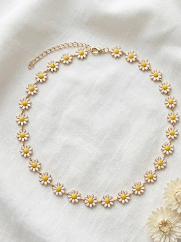 Necklace with daisy flower pendants on a white fabric background