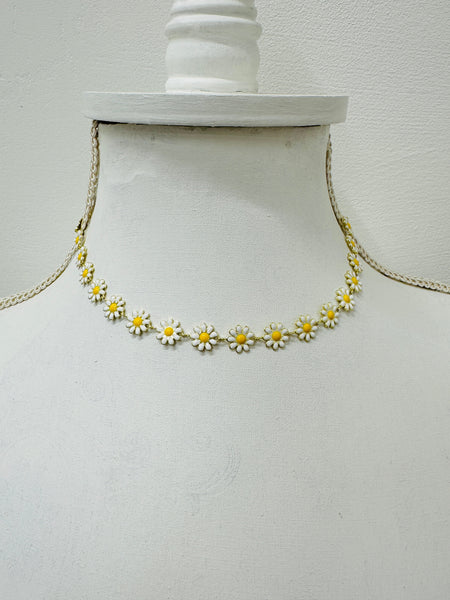 Necklace with daisy flower pendants on a mannequin bust against a white background