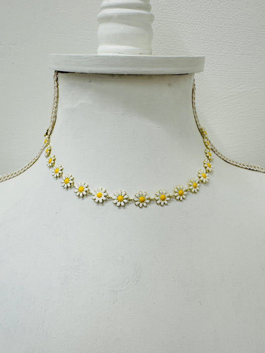 Necklace with daisy flower pendants on a mannequin bust against a white background