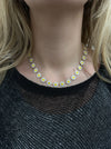 A close-up image of a person wearing a gold-tone chain necklace adorned with daisy flowers.
