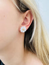 Close-up of a person wearing a daisy flower earring with a plain background
