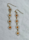 Daisy-shaped earrings on a light gray background