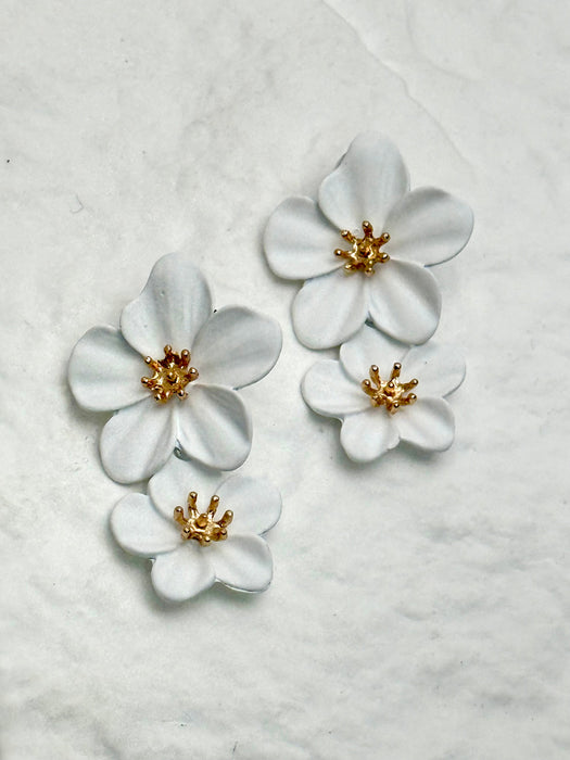 White floral earrings with gold centers on a textured white background