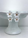 White floral earrings on a white cake stand with a white background