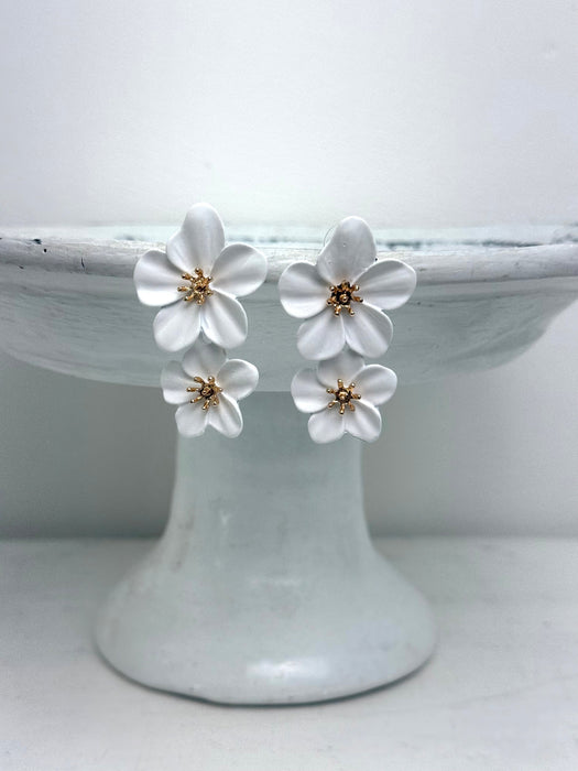 White floral earrings on a white cake stand with a white background